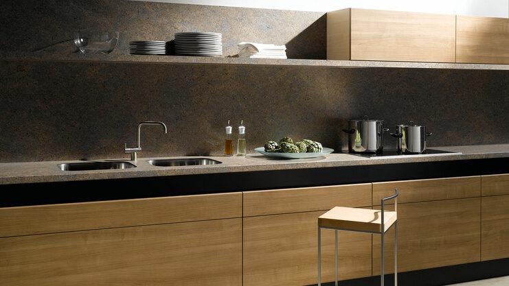 Küchenzeile aus Massivholz mit dunkler Arbeitsplatte Küchenzeile aus Massivholz mit schwarzer Arbeitsplatte, Spülbecken und Wandregal