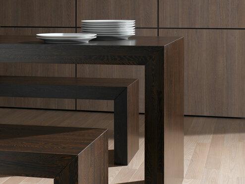 Detailaufnahme eines Esszimmers aus dunklem Massivholz mit Sitzbänken und Einbauschrank im Hintergrund