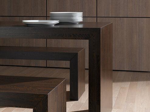 Detailaufnahme eines Esszimmers aus dunklem Massivholz mit Sitzbänken und Einbauschrank im Hintergrund