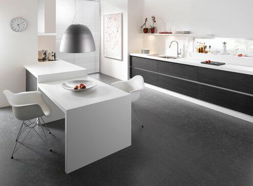 Impression einer einzeiligen Küchengestaltung in schwarz-weiß mit Esstisch für Zwei