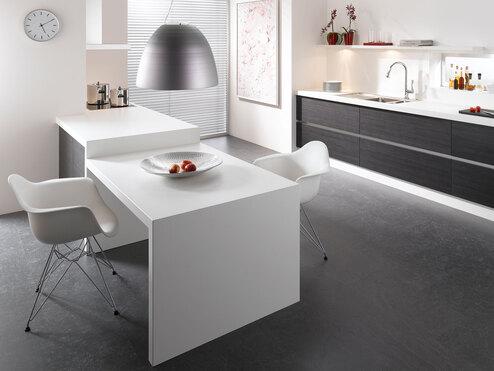 Impression einer einzeiligen Küchengestaltung in schwarz-weiß mit Esstisch für Zwei