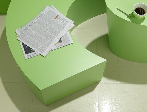 Detailaufnahme einer grünen Sitzbank mit Papierdokumenten und Tischausschnitt mit Kaffeetasse