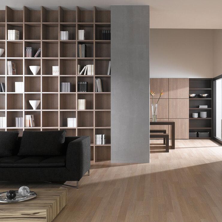 Offene Wohnraumimpression mit Einbauregal für Bücher und Dekoration in Trennwand mit hellem Holzboden