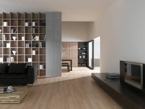 Offene Wohnraumimpression mit Einbauregal für Bücher und Dekoration in Trennwand mit hellem Holzboden